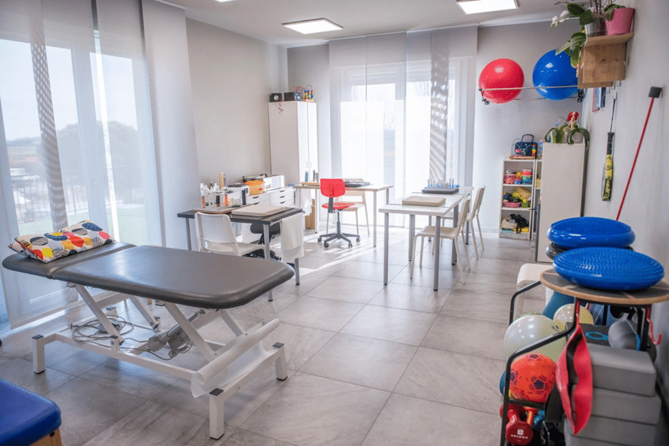 A clean, modern treatment room demonstrating medical acupuncture needles in the lower back alongside custom orthotics.